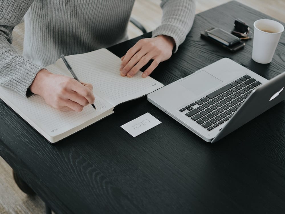 A person writing in a notebook at a desk