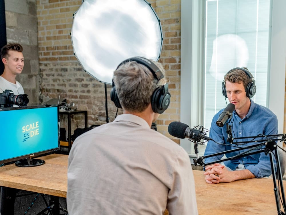 Two people recording a podcast at a table with microphones